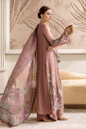 Woman in a pink embroidered traditional outfit with a matching dupatta in an elegant room.