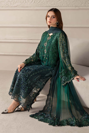 Woman wearing a green embroidered traditional outfit sitting on a white couch.
